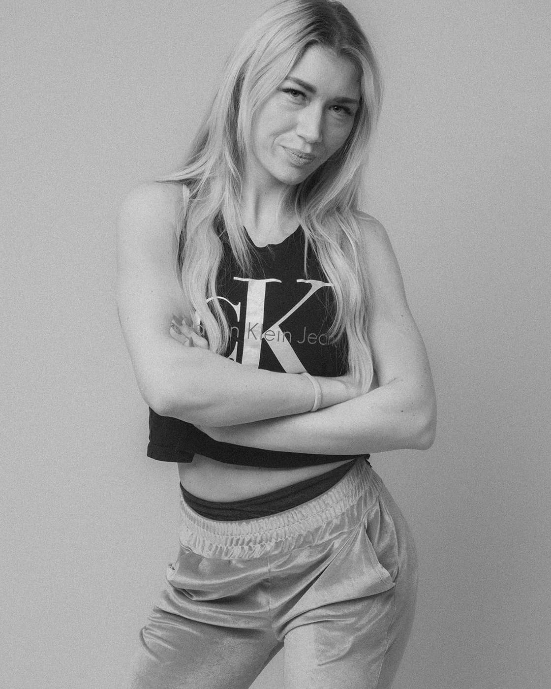 Black and white portrait of a blonde woman standing with crossed arms.