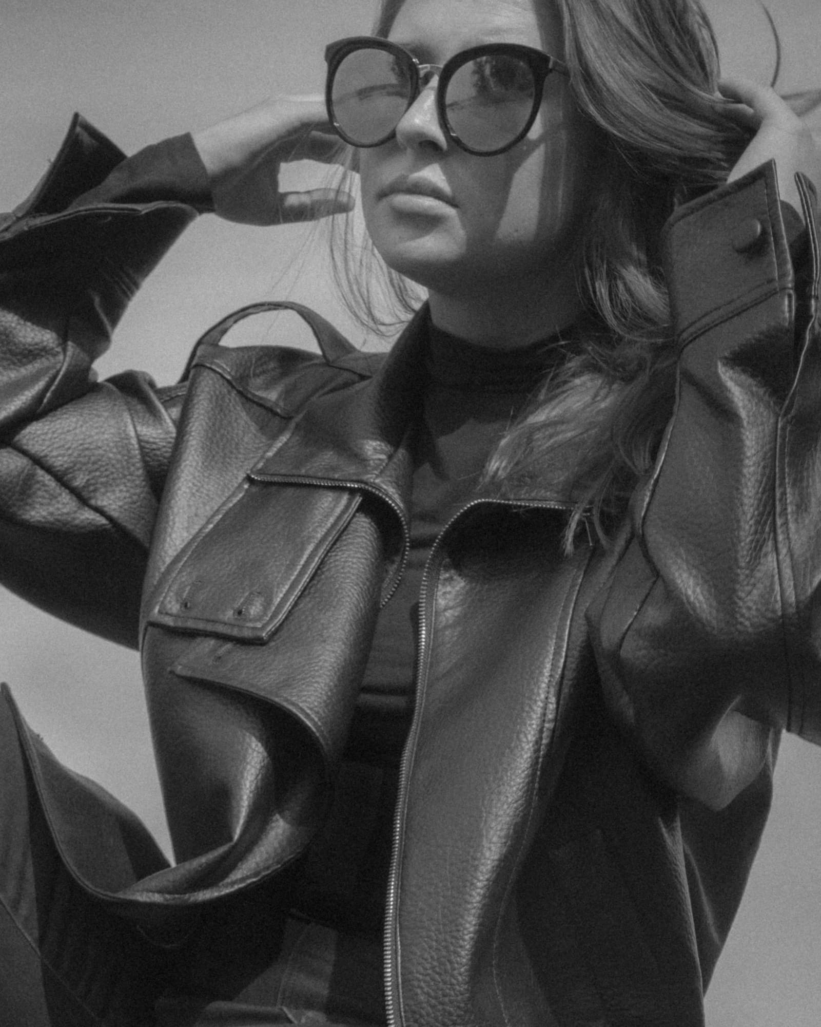 Black and white portrait of a woman in sunglasses and a leather jacket.