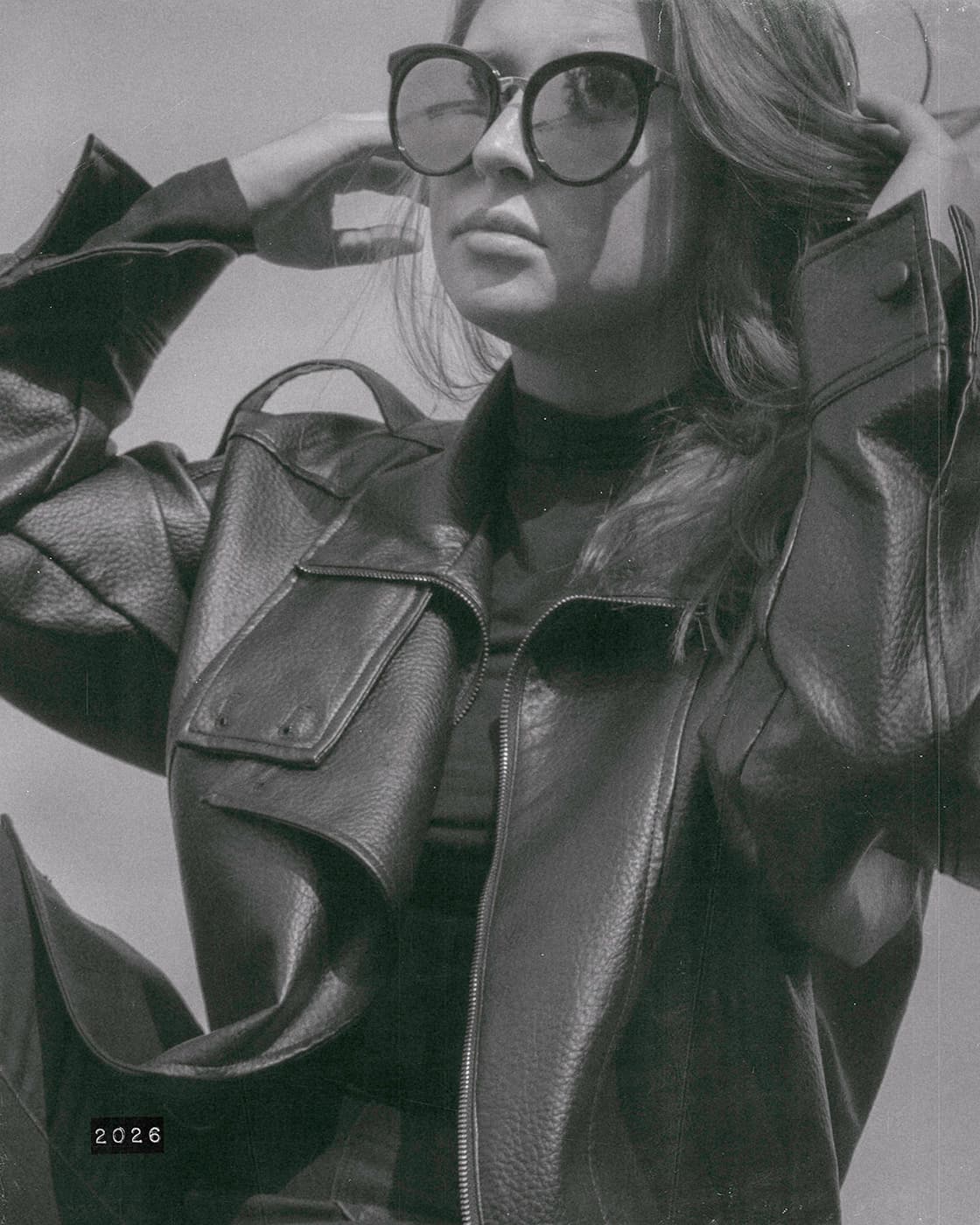 Black and white portrait of a woman in sunglasses and a leather jacket.