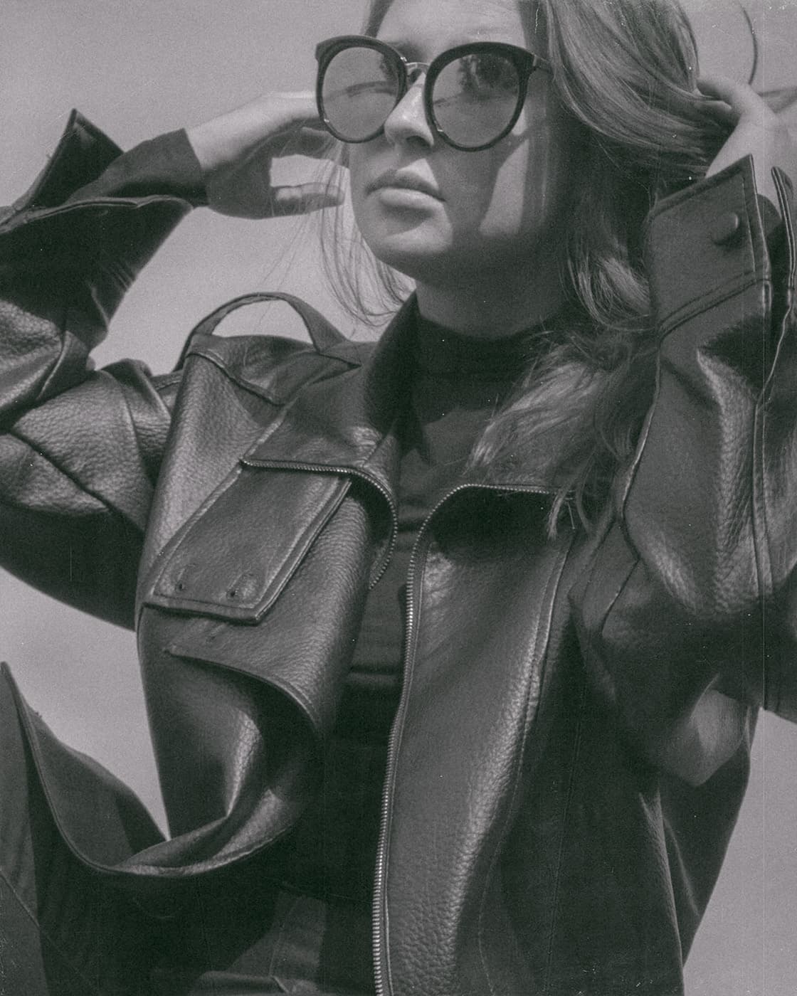 Black and white portrait of a woman in sunglasses and a leather jacket.