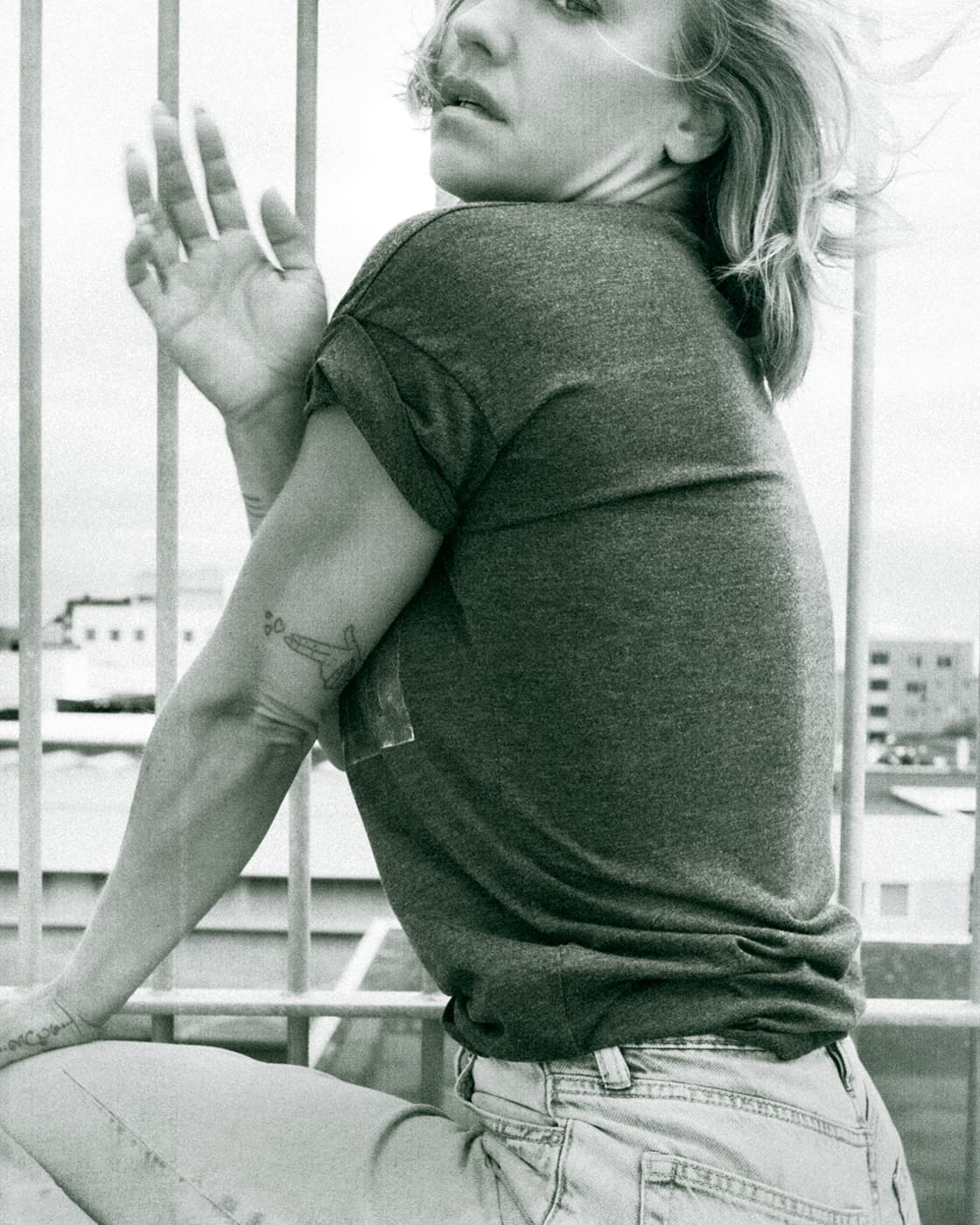 Black and white portrait of a woman seated by a balcony railing.