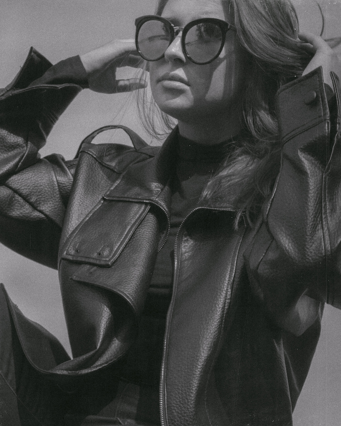 Black and white portrait of a woman in sunglasses and a leather jacket.